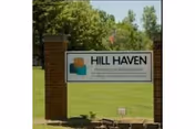 Hill Haven entrance sign between brick pillars with green lawn and trees.