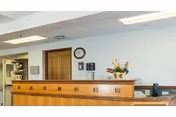 Reception area with a wooden front desk, clock, and flower arrangement.