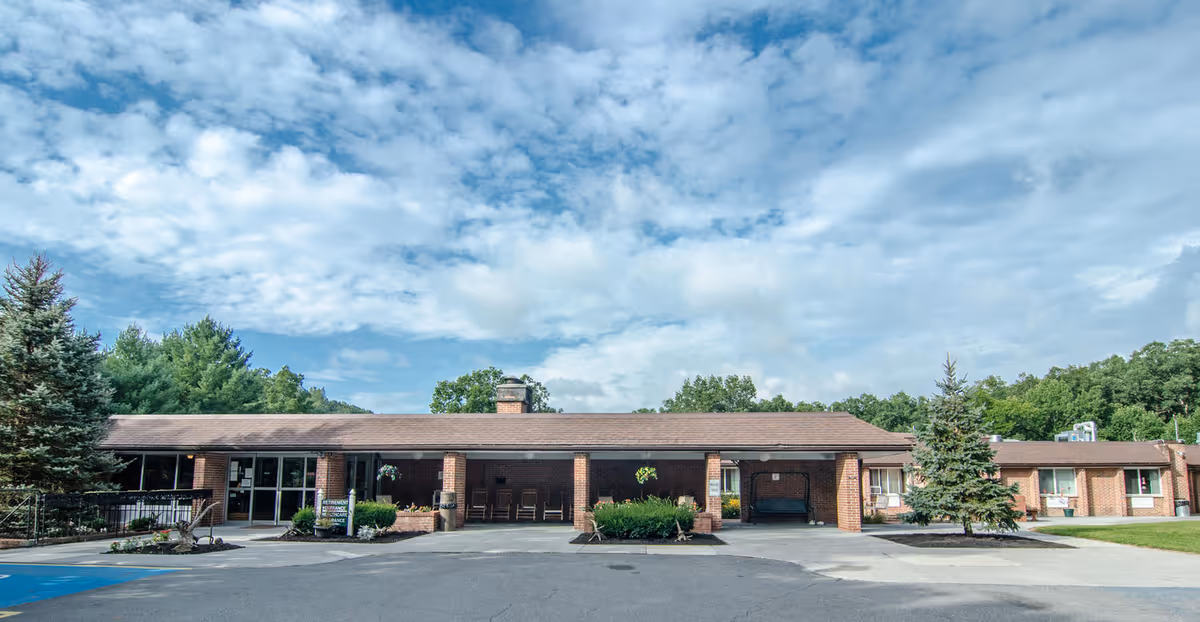 Front exterior view of Glenwood Park facility showing a single-story brick building with a covered entrance, surrounded by trees and a partly cloudy sky.