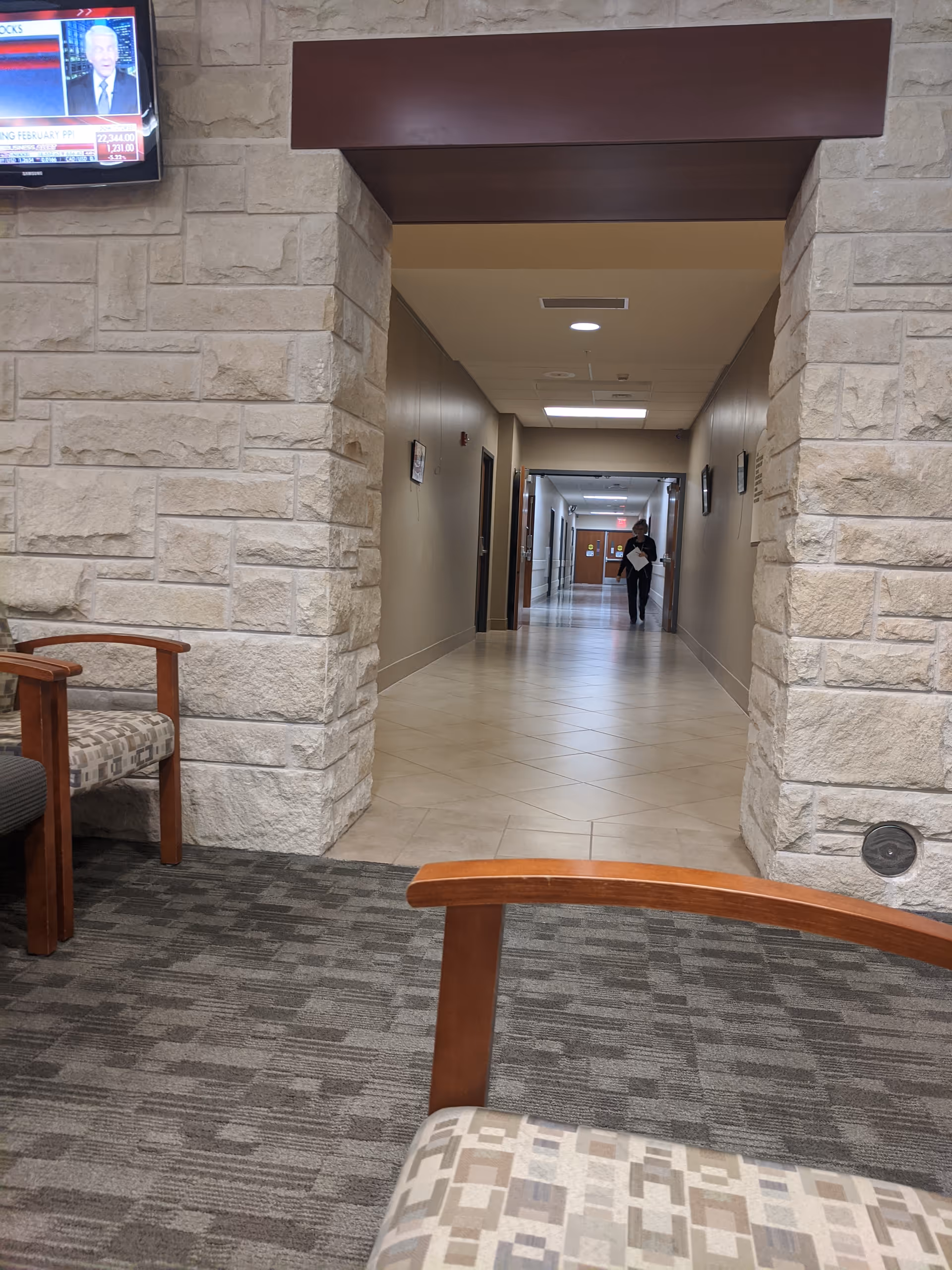 Interior hallway of a senior living facility with seating and a distant person.