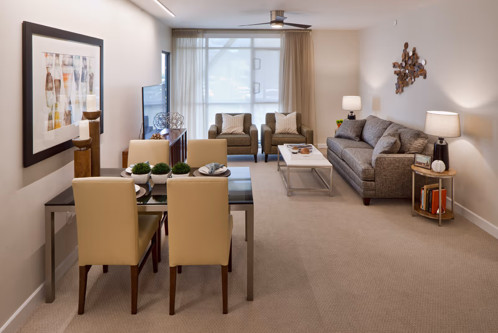 Bright furnished living and dining area with a sofa, two armchairs, coffee table, and a four-seat dining table.