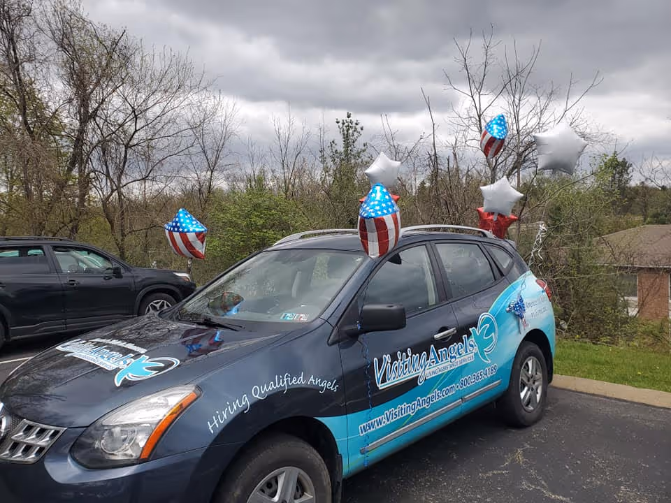 Promotional Visiting Angels car decorated with star-shaped balloons in a parking lot