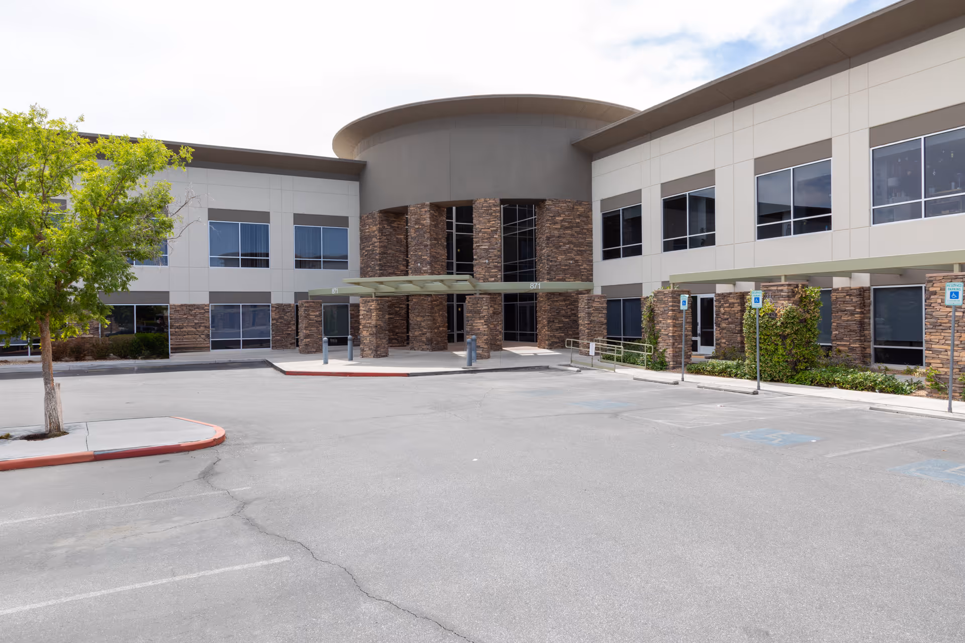 Front view of a modern medical facility with brick entrance and adjacent parking.