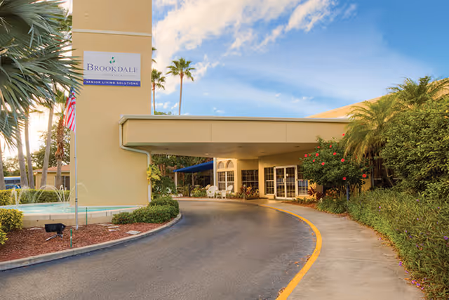 Exterior view of Brookdale Palma Sola entrance with curved driveway and palm trees