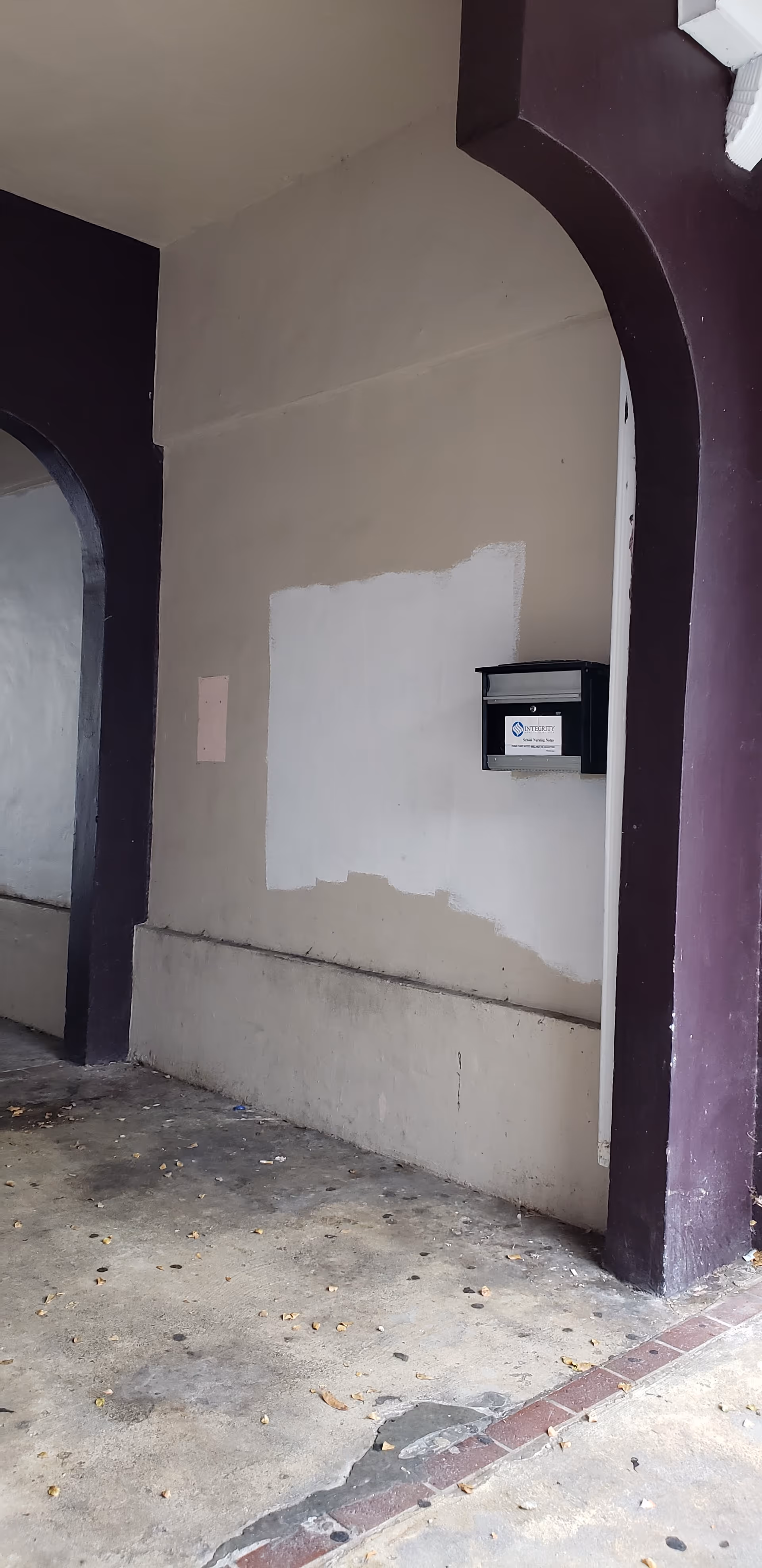 An exterior wall features purple arches, doorway, and a mounted mailbox.