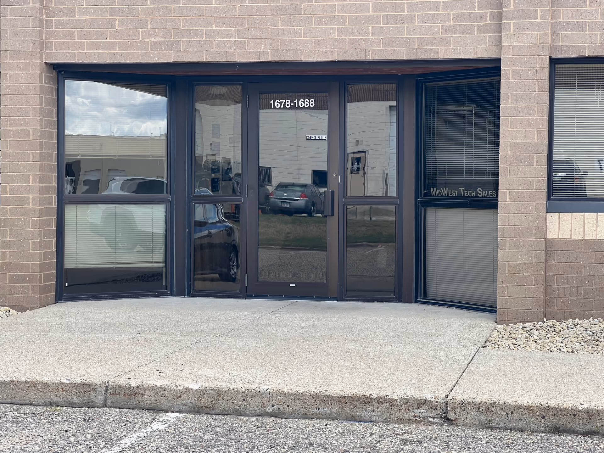 Exterior brick facade with glass doors and windows, address numbers visible above entrance.