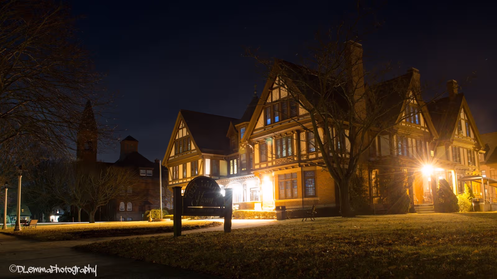 Night Exterior view of Our Lady's Haven, Tudor-style senior living building with illuminated entrance.