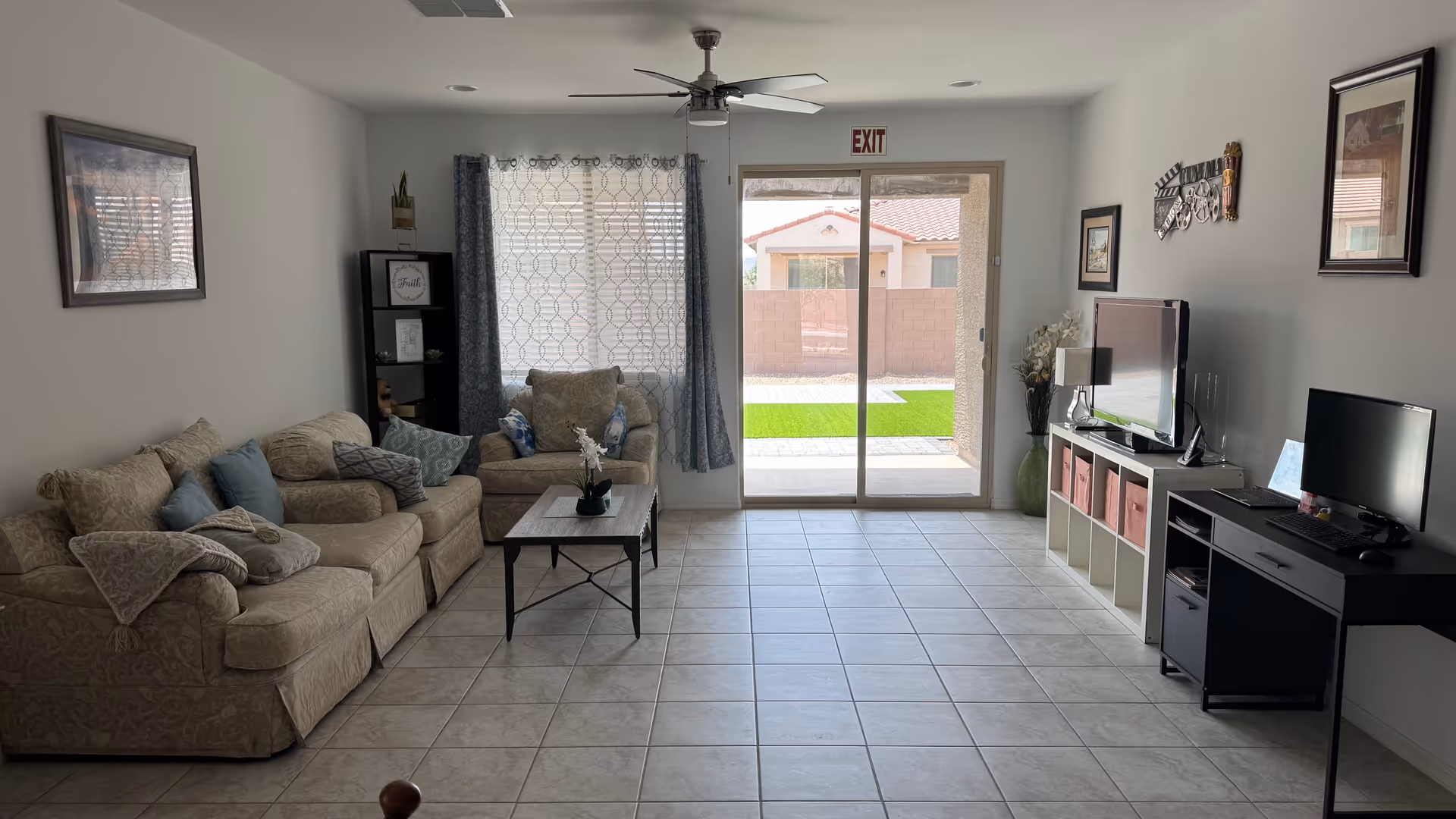 Cozy living room with beige sofa, coffee table, TV, and sliding glass door to outside.