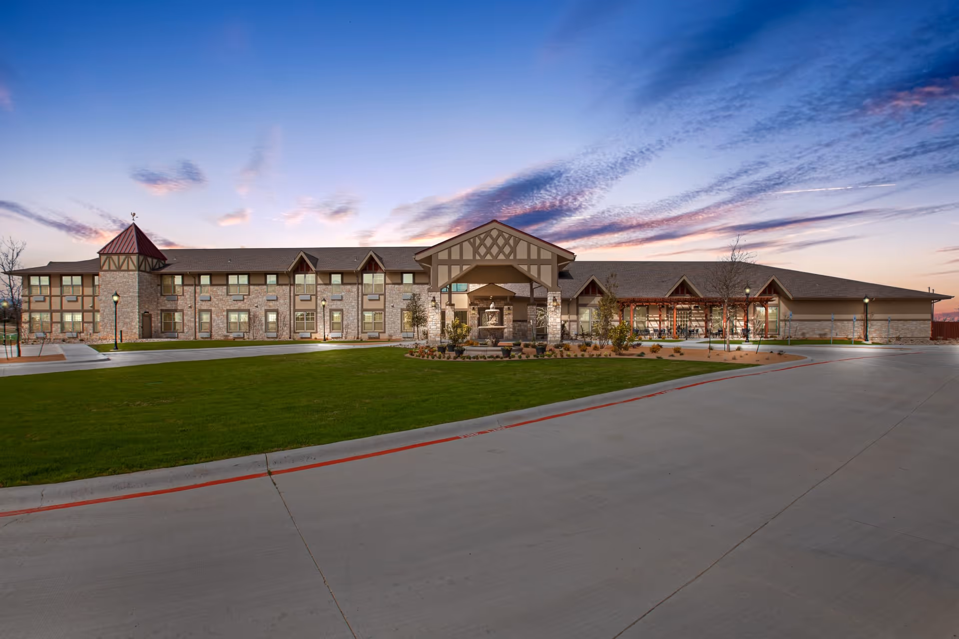 Exterior view of The Villages of Windcrest, showing the front of the building, lawn, and driveway.