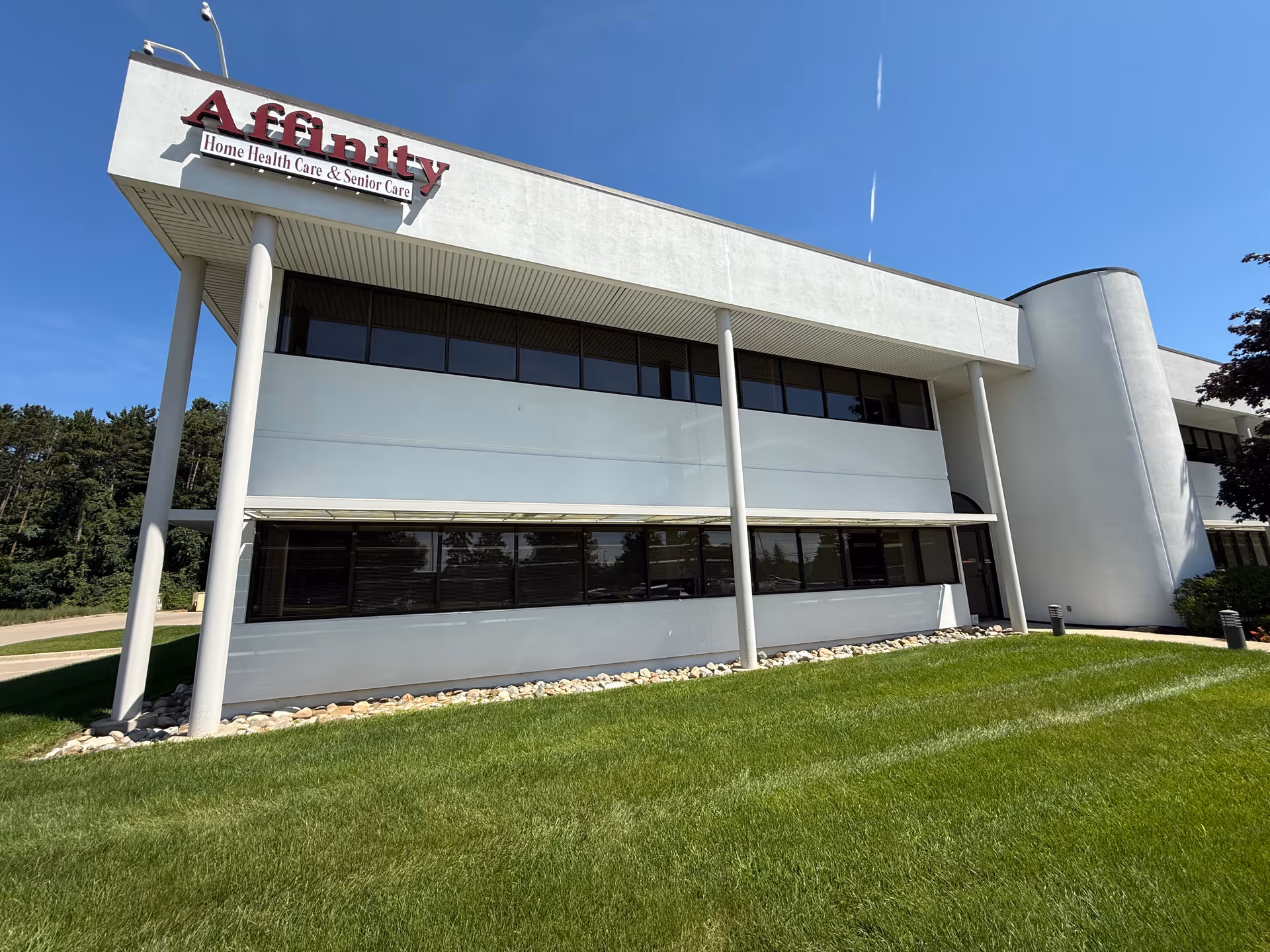 Modern Affinity Home Care Agency building exterior with sign, white facade, glass windows, and lawn.