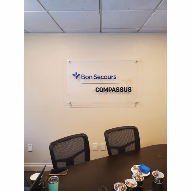 Conference table with two chairs and a Bon Secours Compassus sign on the wall.
