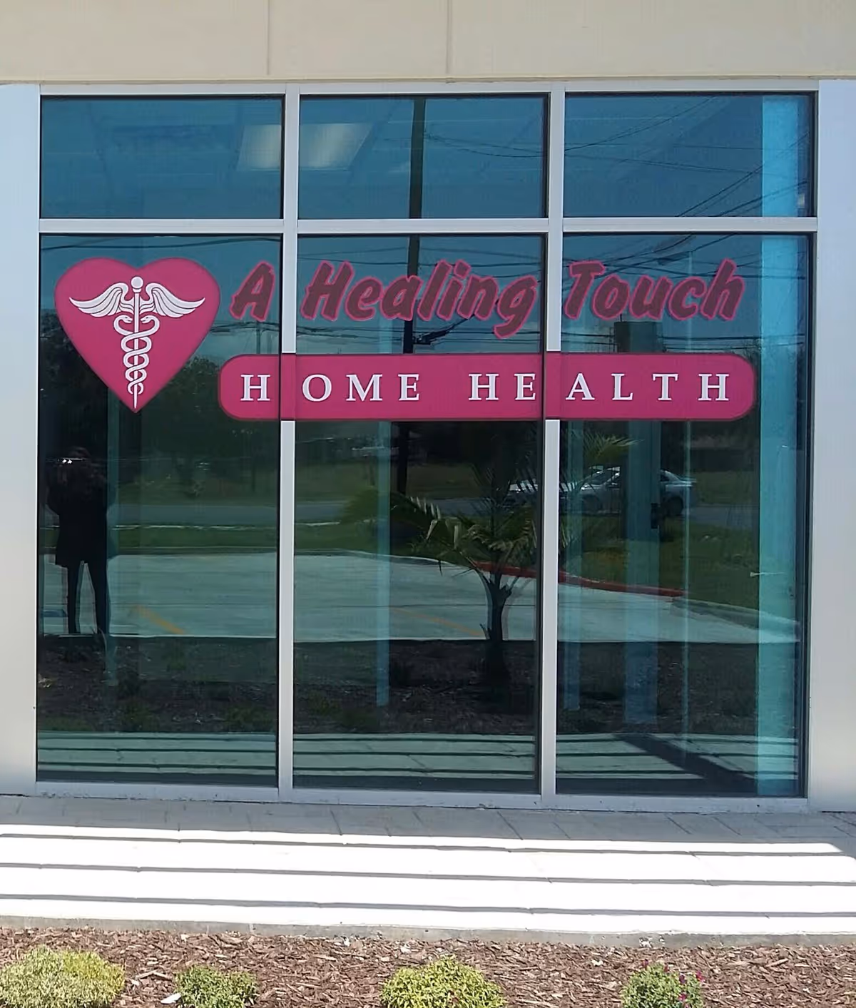 Glass storefront displaying pink signage for A Healing Touch Home Health on exterior