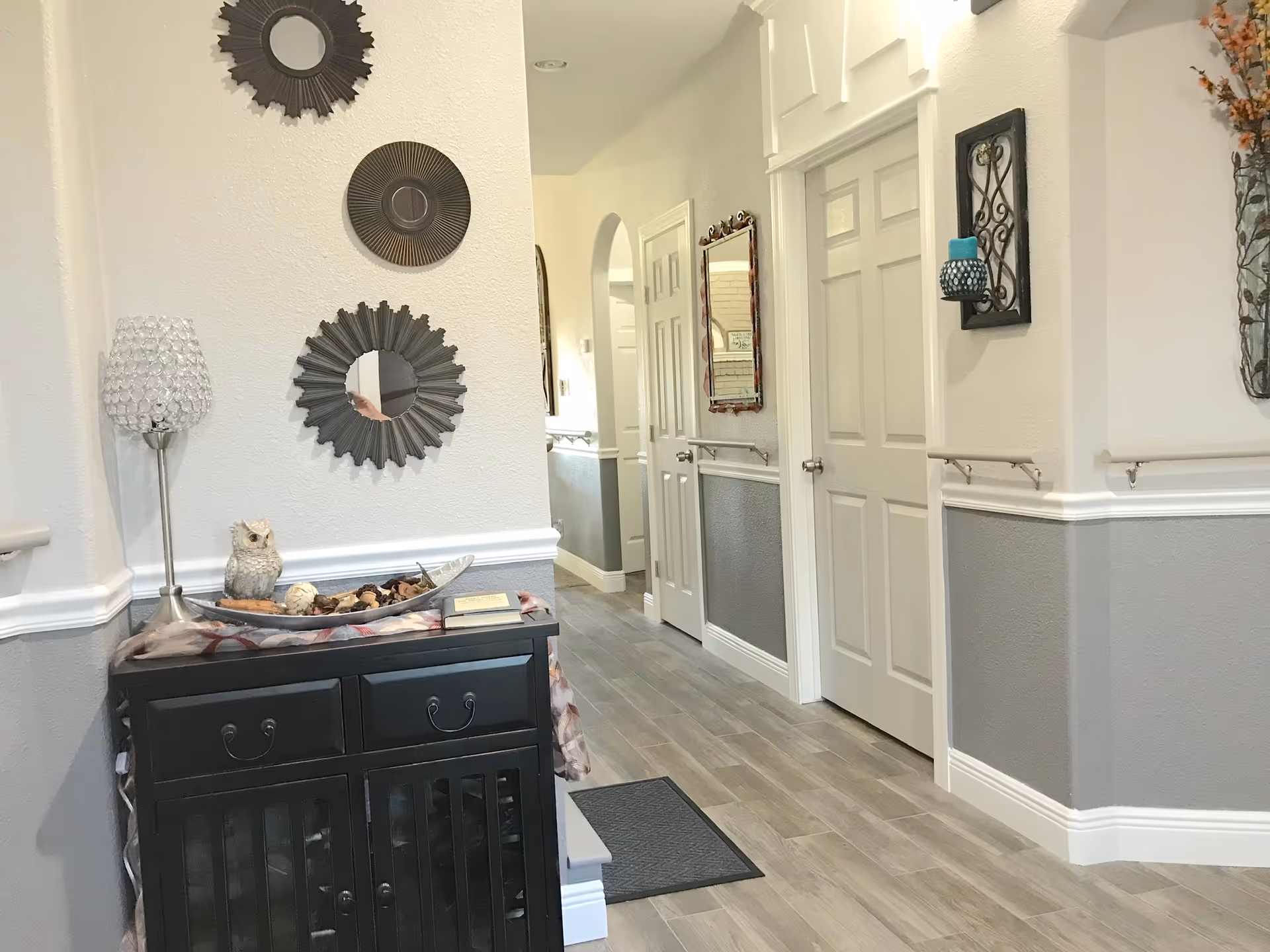 Bright hallway in a senior living facility with decorative wall art and a console table.