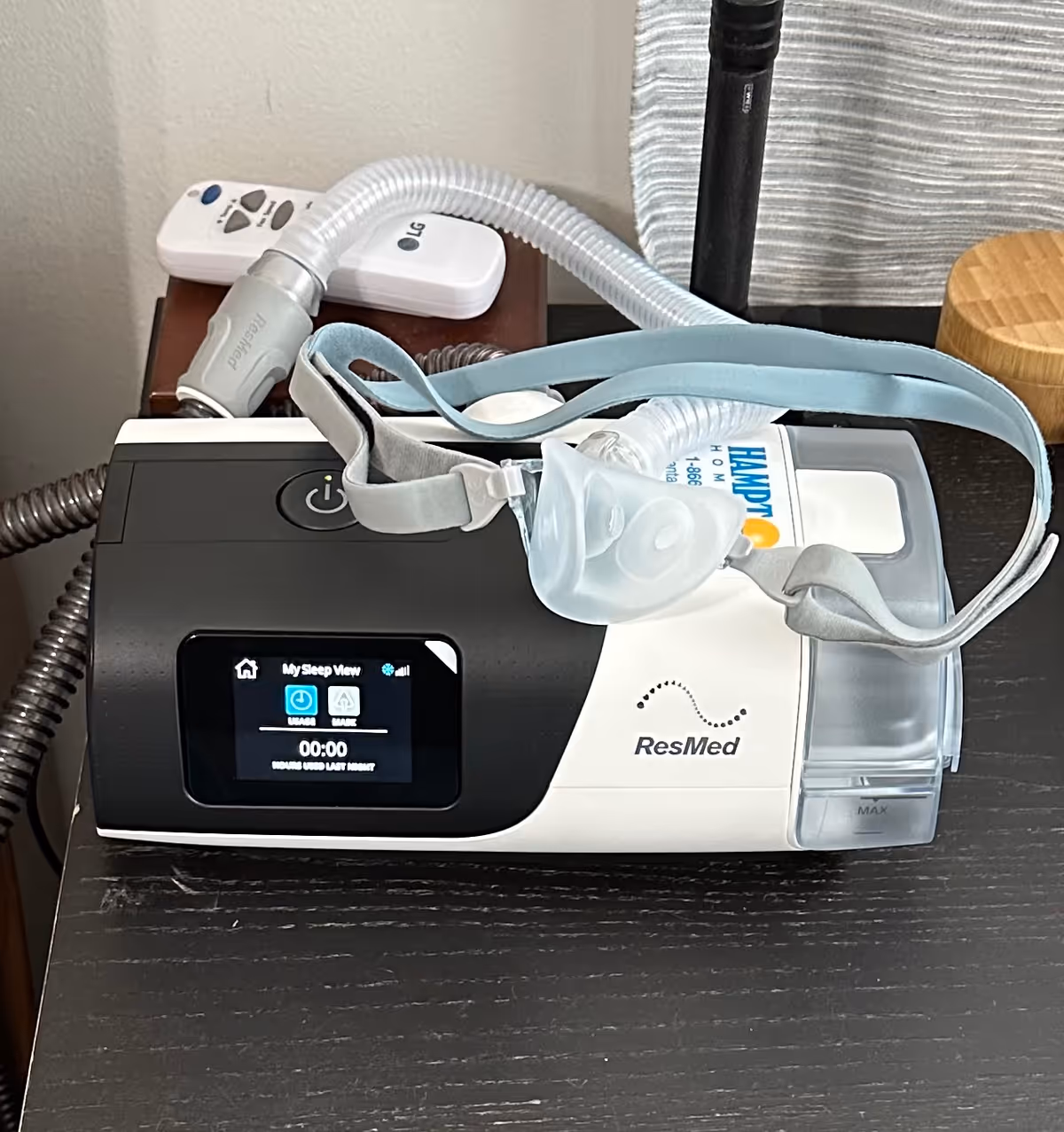 Close-up of a ResMed sleep apnea device with mask on a nightstand.