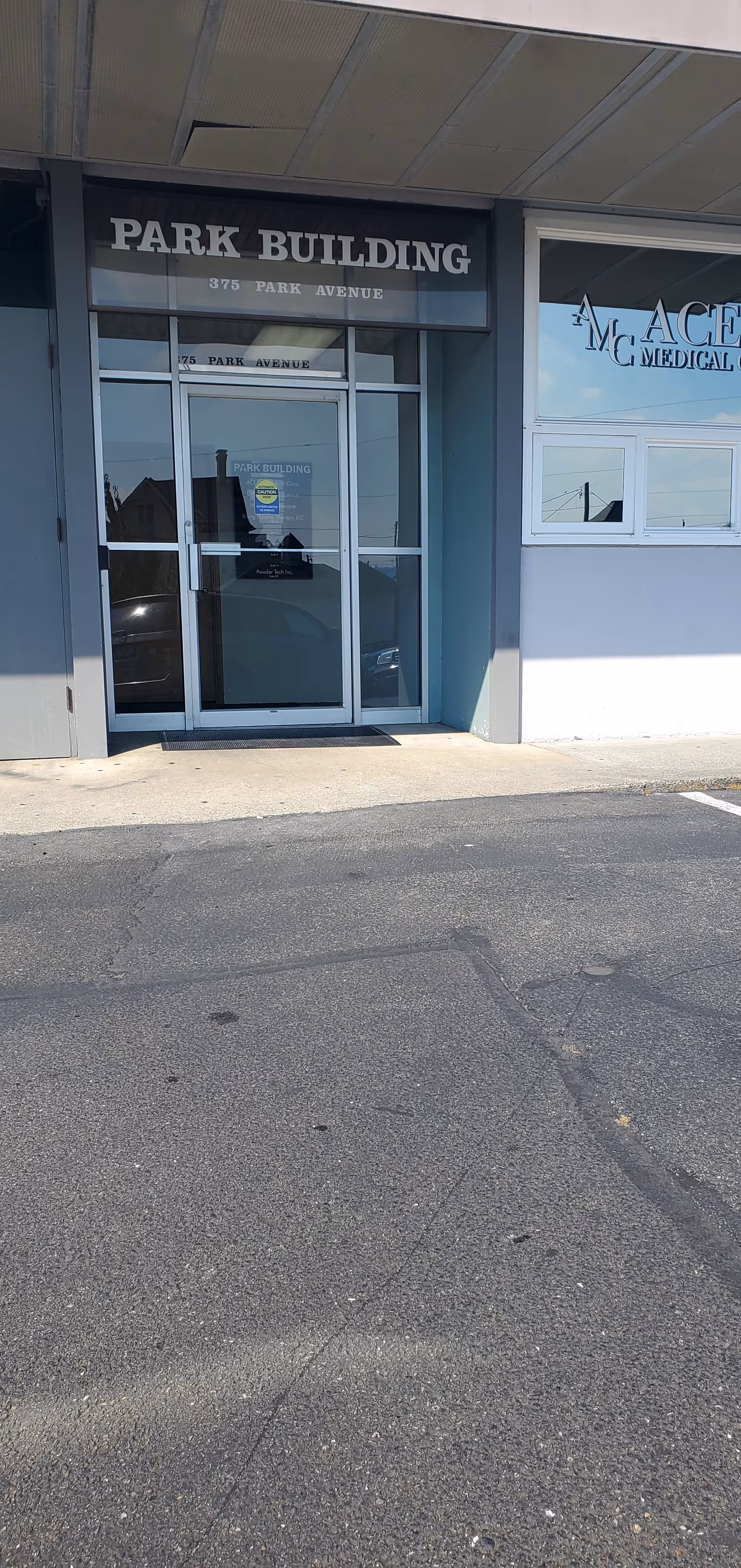 Front entrance of Park Building with glass doors and a medical storefront beside it.