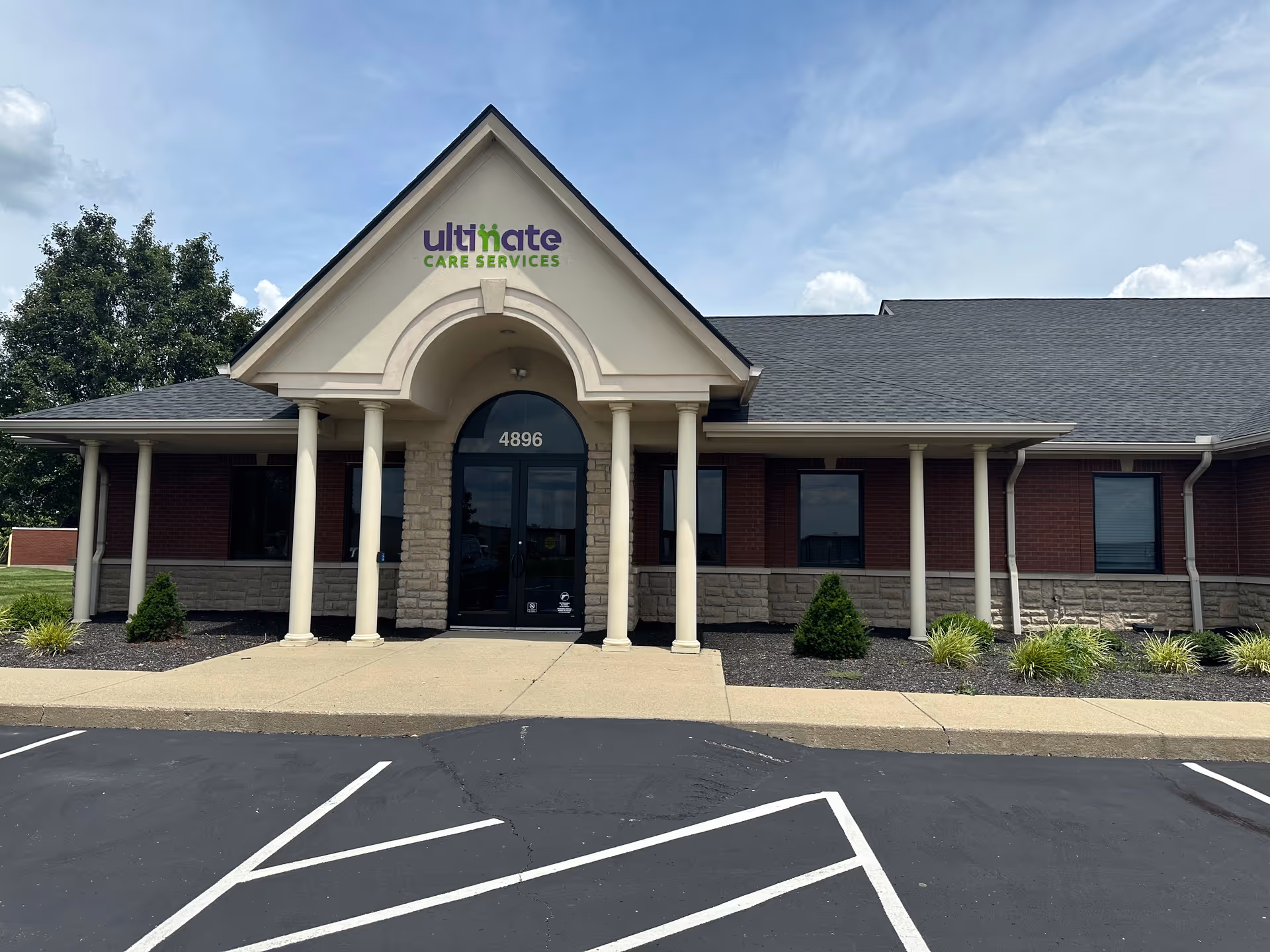 Front view of Ultimate Care Services building with arched entrance and pillars.