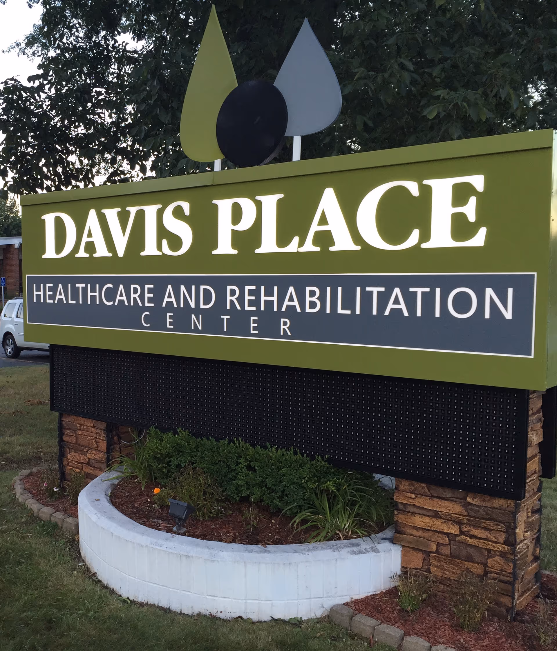 Large green Davis Place sign for Healthcare and Rehabilitation Center with landscaping.