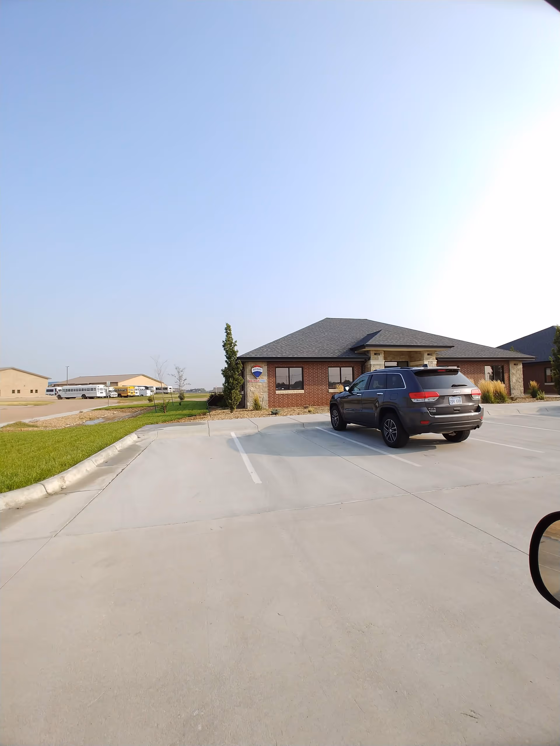 Front exterior of a brick facility with a parked SUV in the lot.