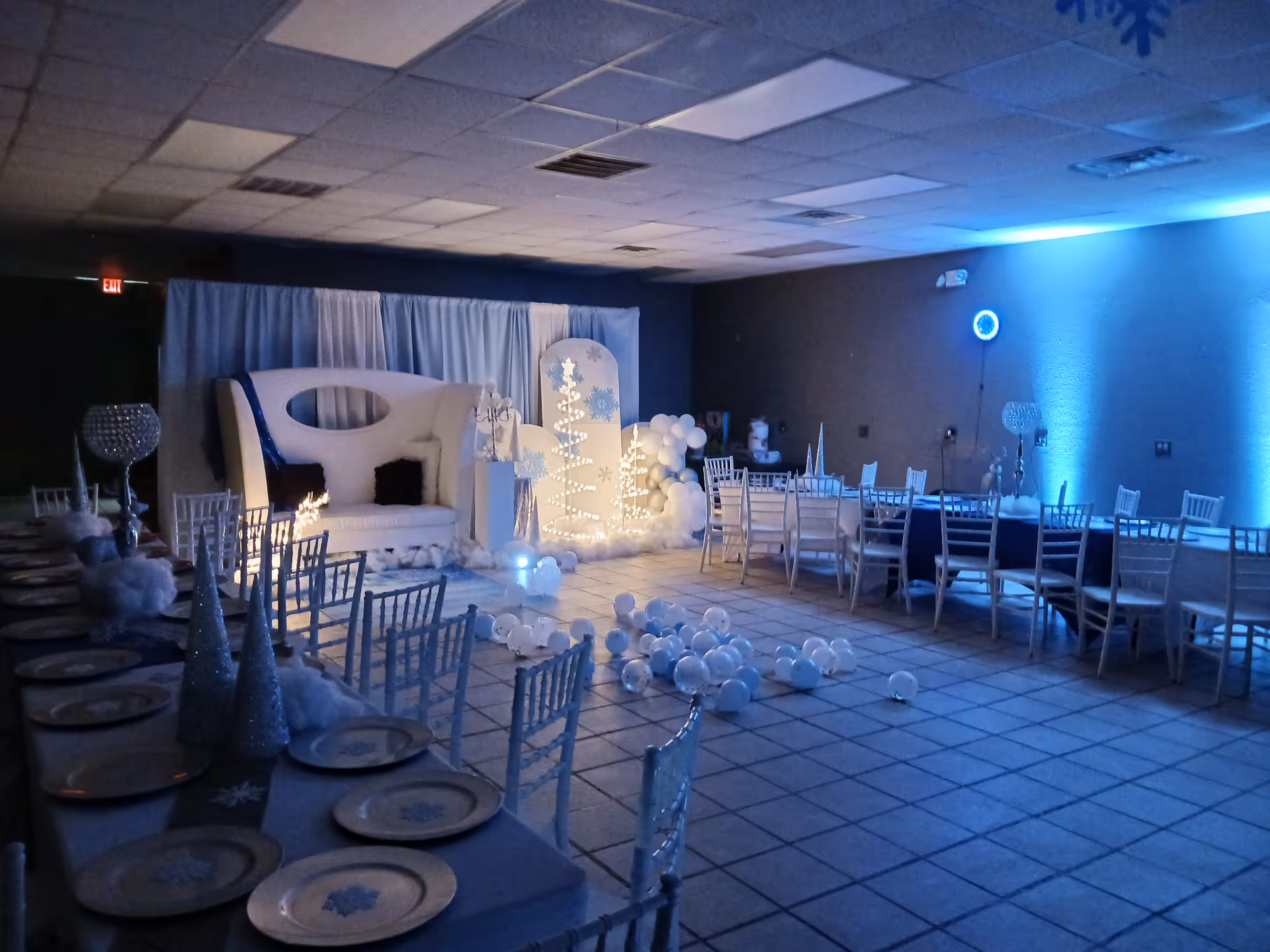 Winter-themed event setup in a senior living facility hall with white decor and balloons.