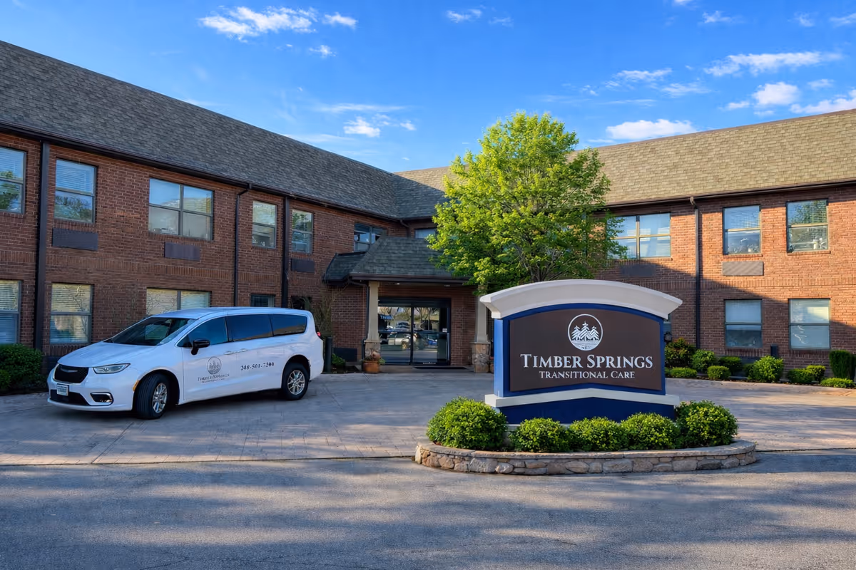 Two-story brick facility with Timber Springs Transitional Care sign and a white service van.