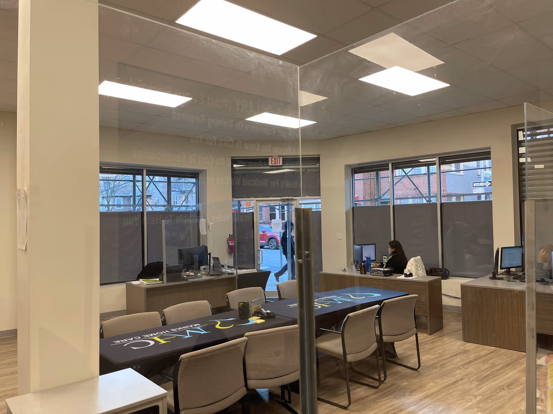 Interior office area in a senior care facility with desks, computers, and a glass partition.