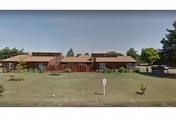Single-story brick Diversicare of Larned facility with manicured lawn and a parked car