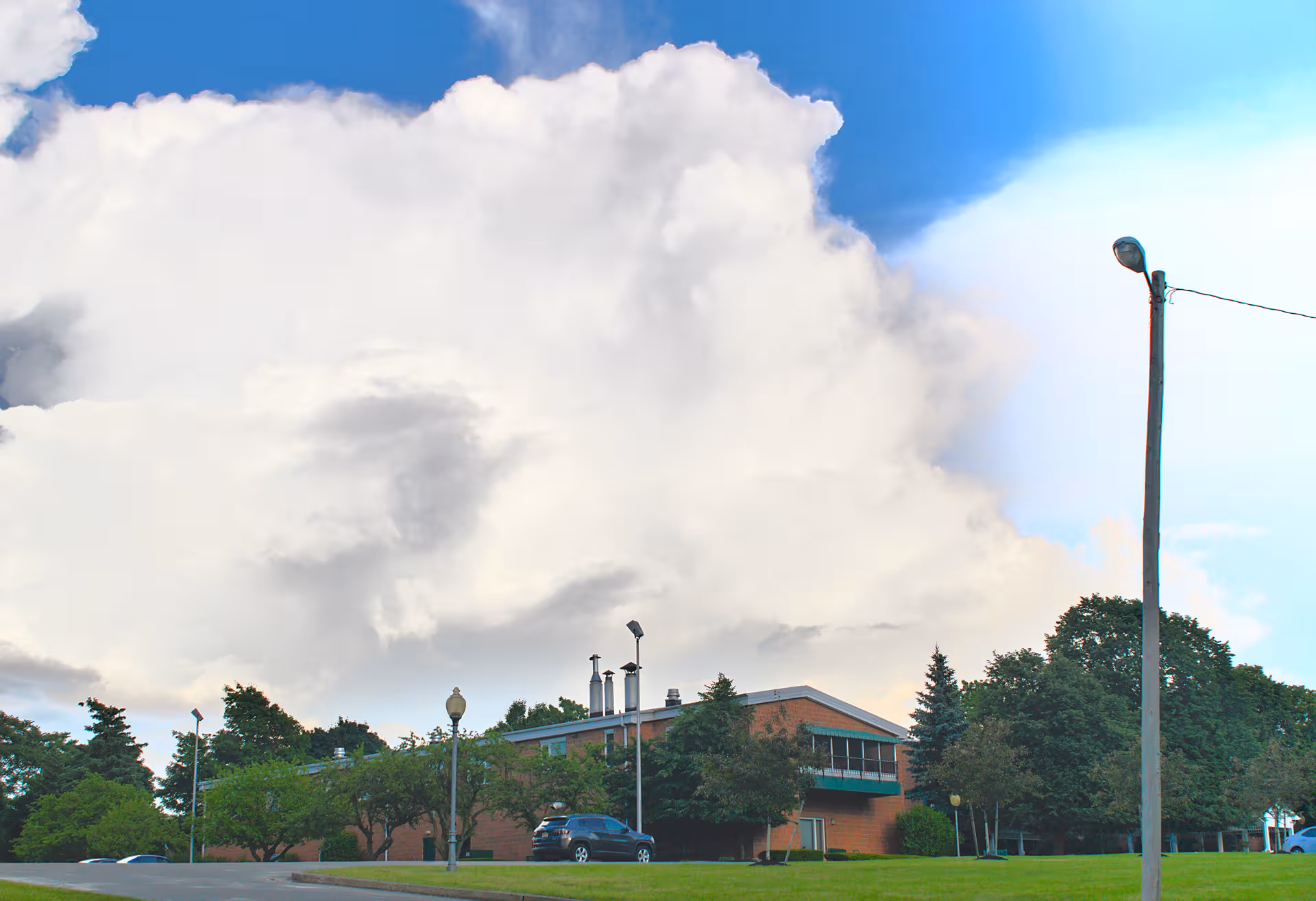 Exterior view of Blocher Homes building, parking lot, trees, under a cloudy sky.