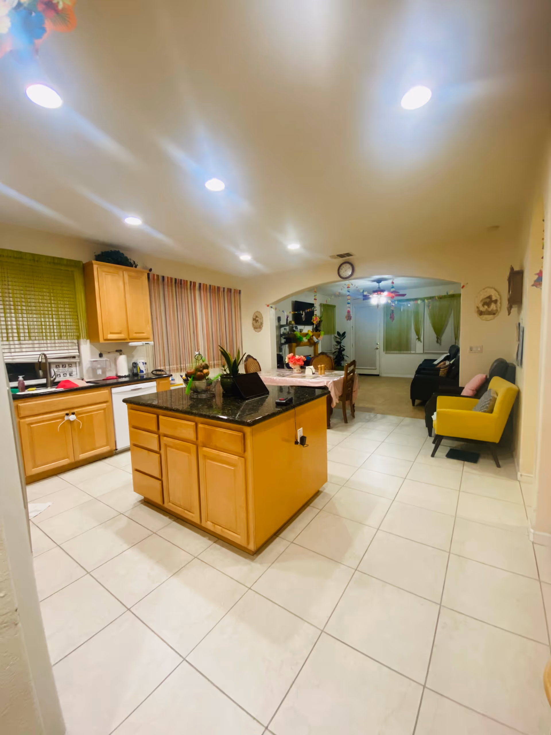 Open kitchen with island, wooden cabinets, and connected dining and living areas.