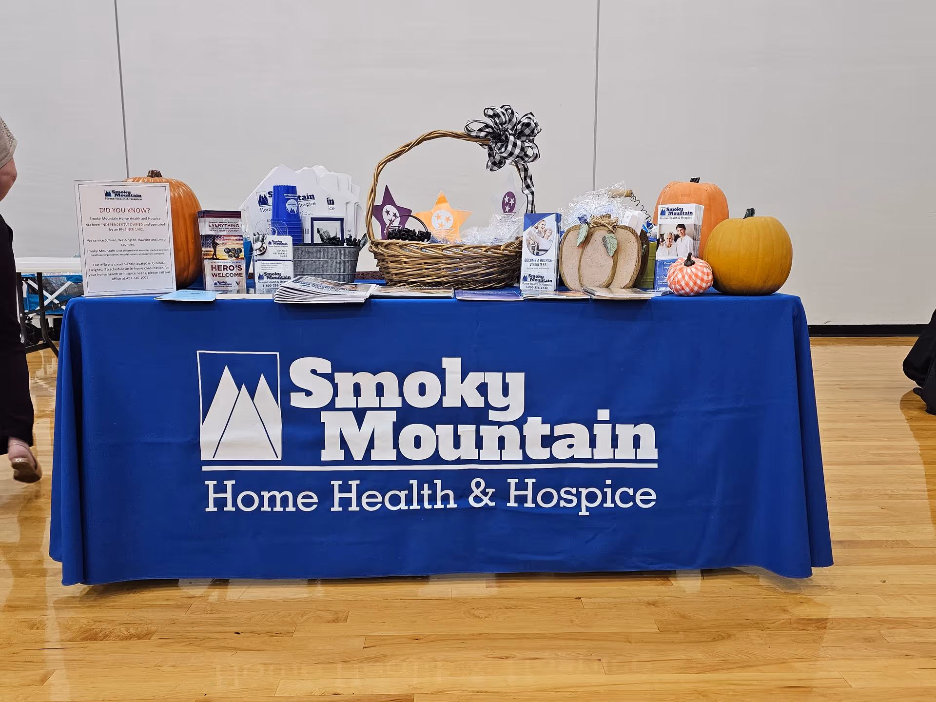 Indoor event table with a blue Smoky Mountain Home Health & Hospice display and pumpkins.