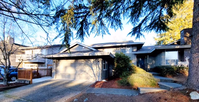 Exterior view of a senior living facility with garages, steps, and landscaping.