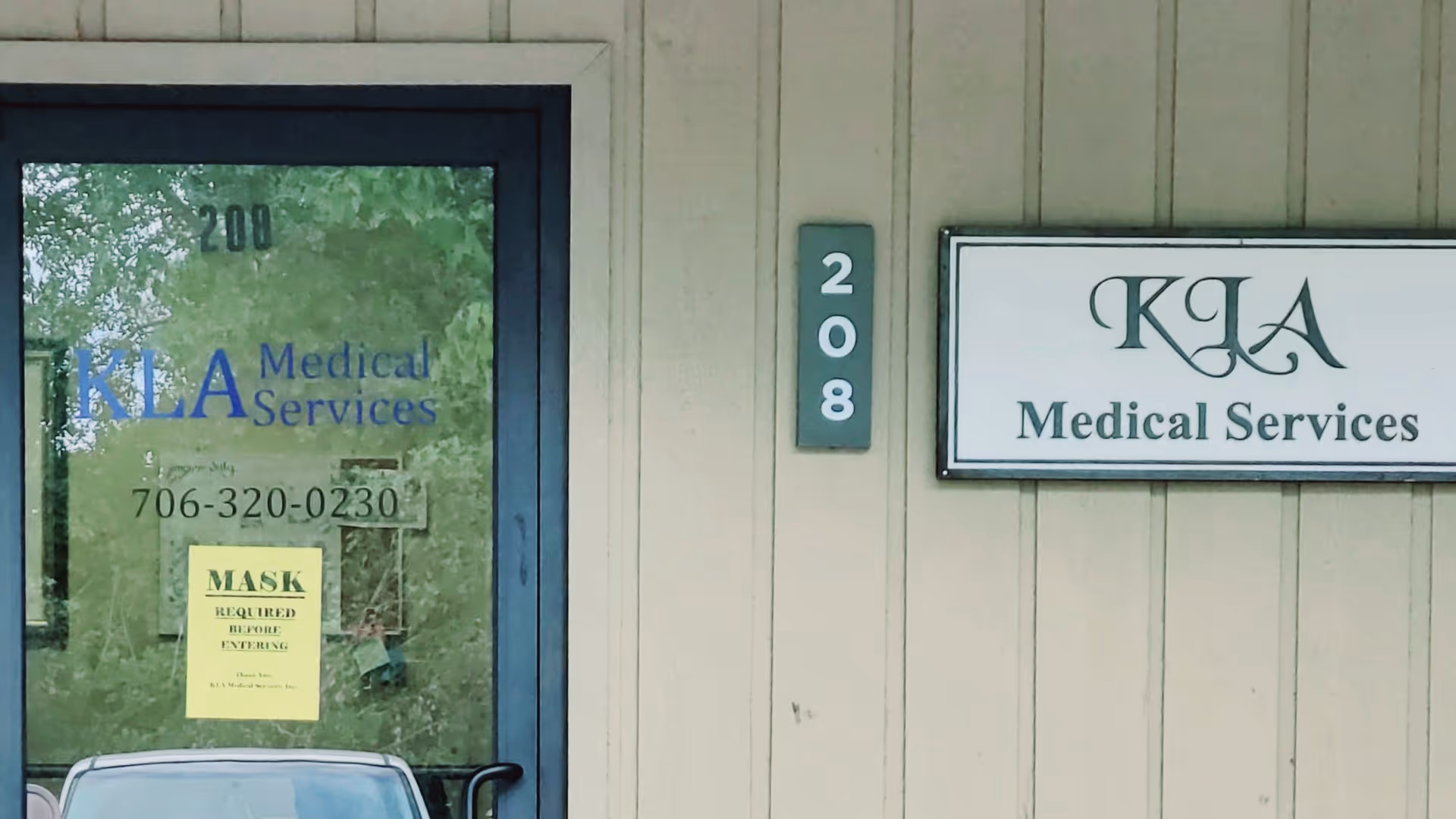Exterior view of a beige building with a glass door and KLA Medical Services signage.