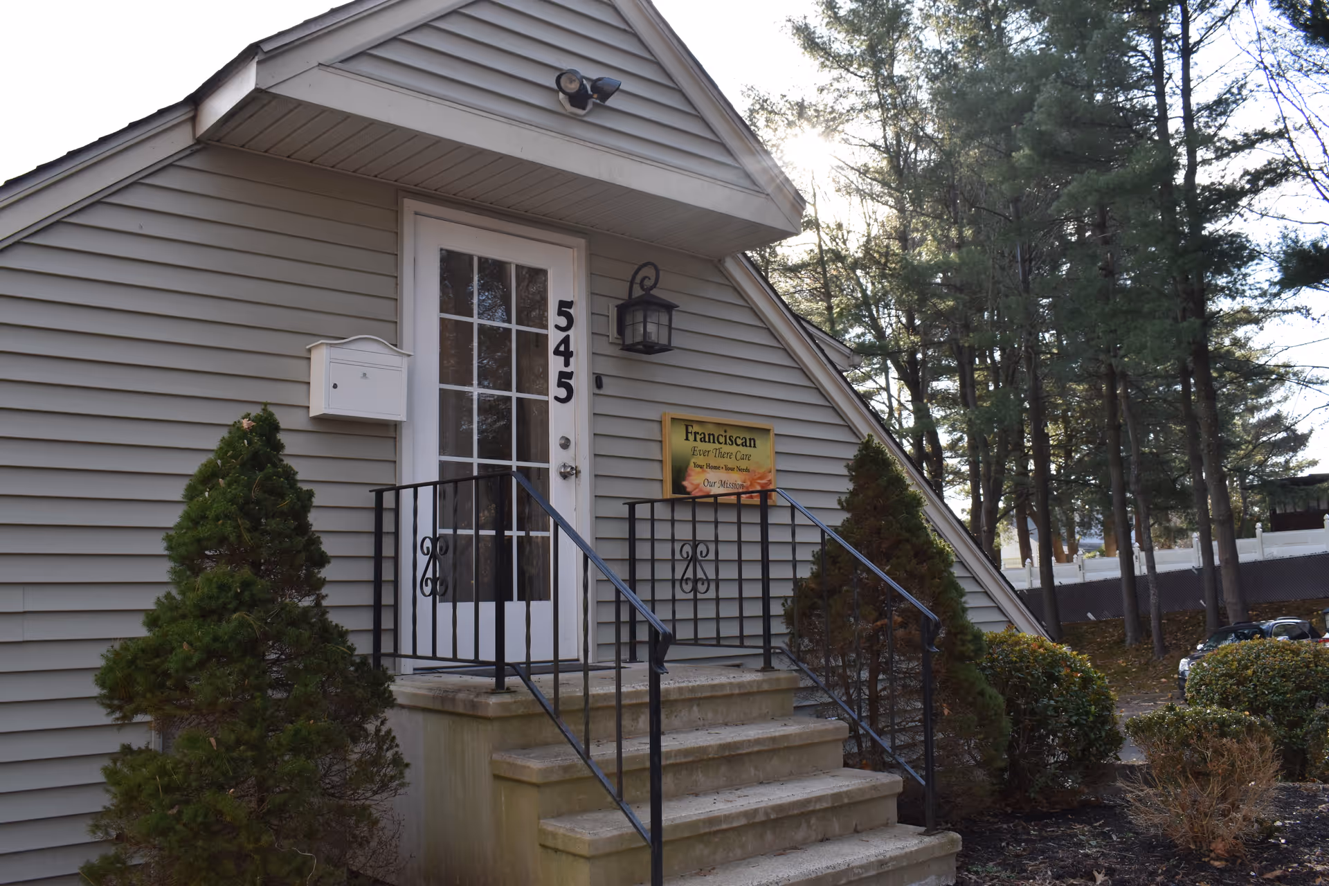 Front entrance of a Franciscan senior care facility with stairs and sign.