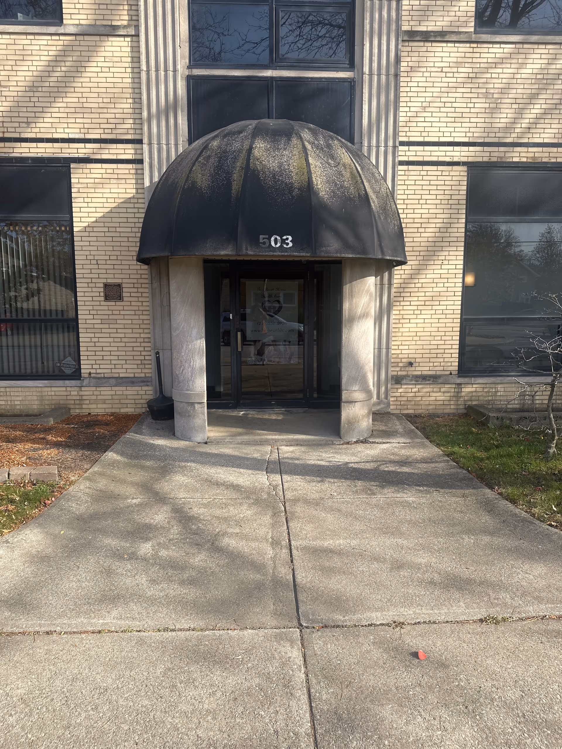 Brick building entrance with a black domed canopy and glass doors labeled 503.