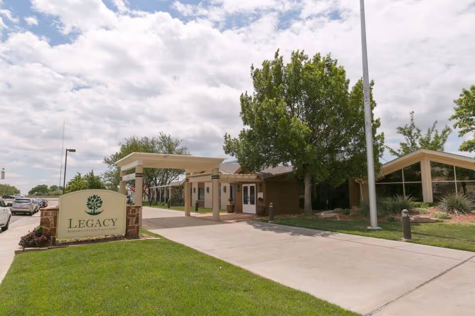 Exterior view of Legacy Rehabilitation and Living entrance with signage and trees.