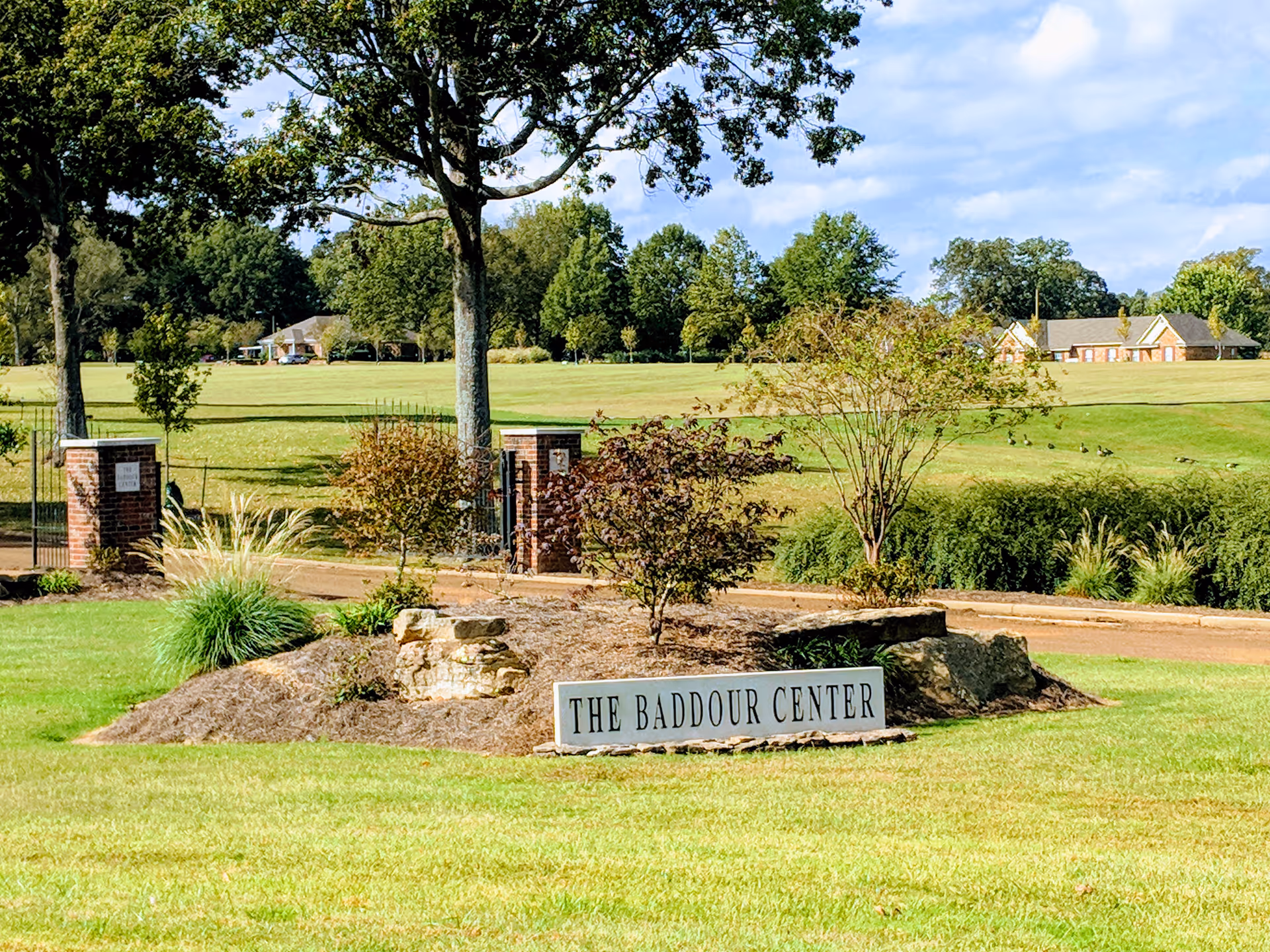 Entrance sign for The Baddour Center with landscaped rocks, trees, and green lawn