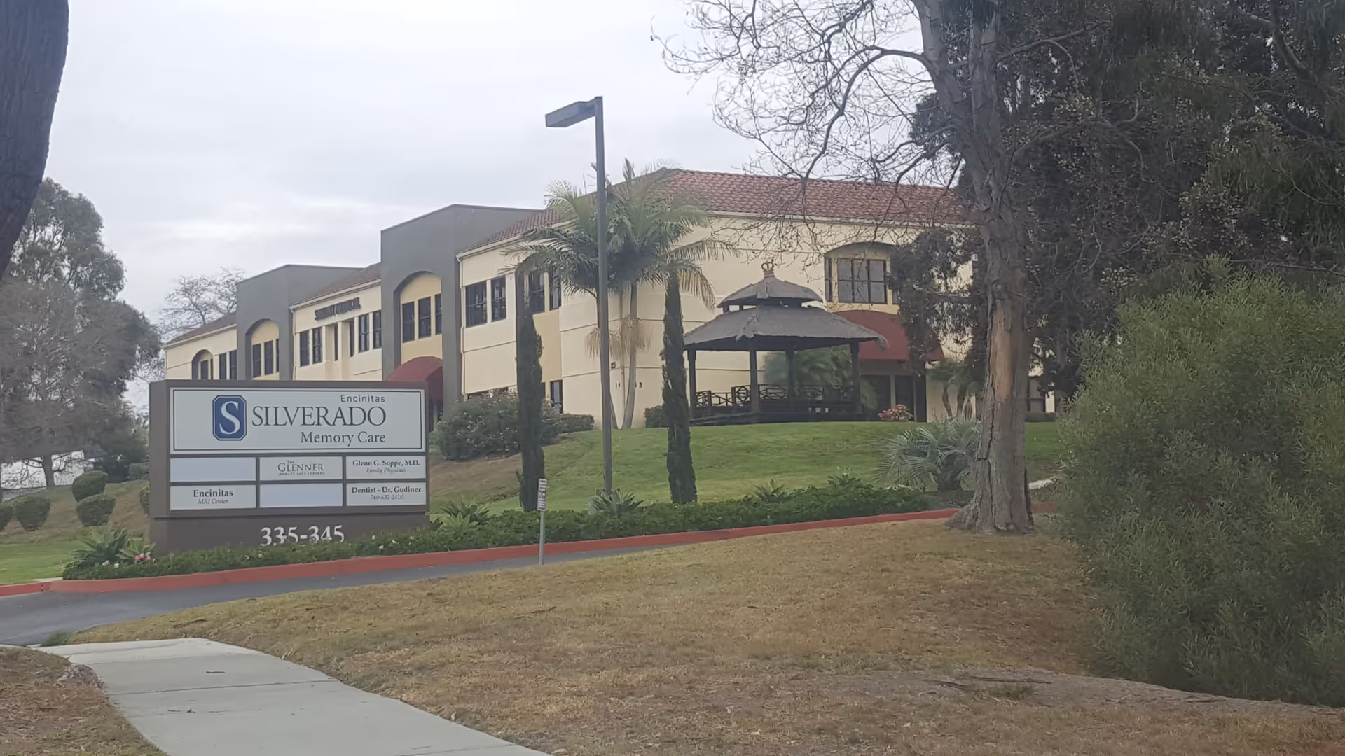 Exterior view of Silverado Memory Care Community with sign, lawn, and gazebo.