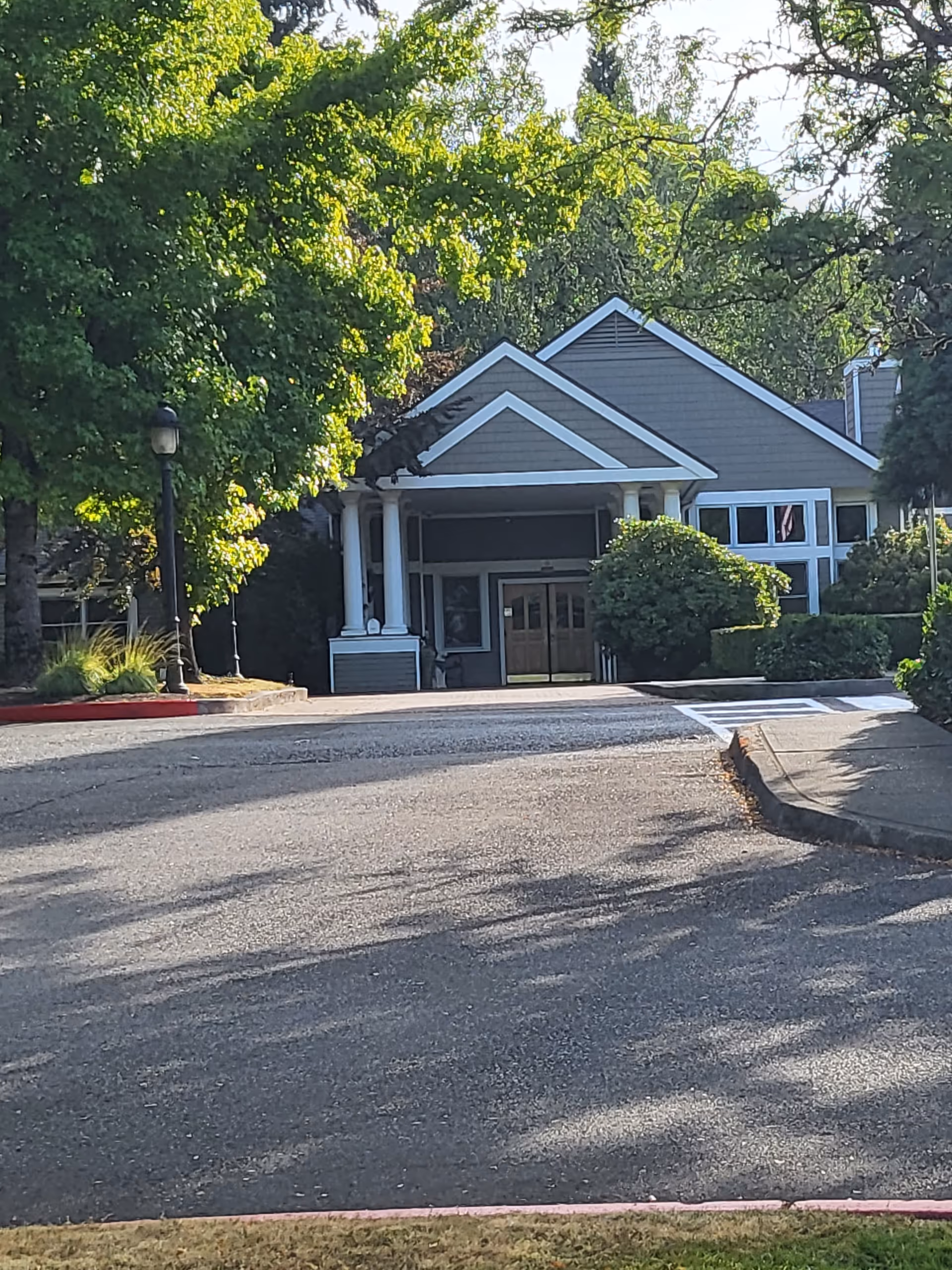 Exterior view of EvergreenHealth Hospice Services building front with covered entrance and trees.