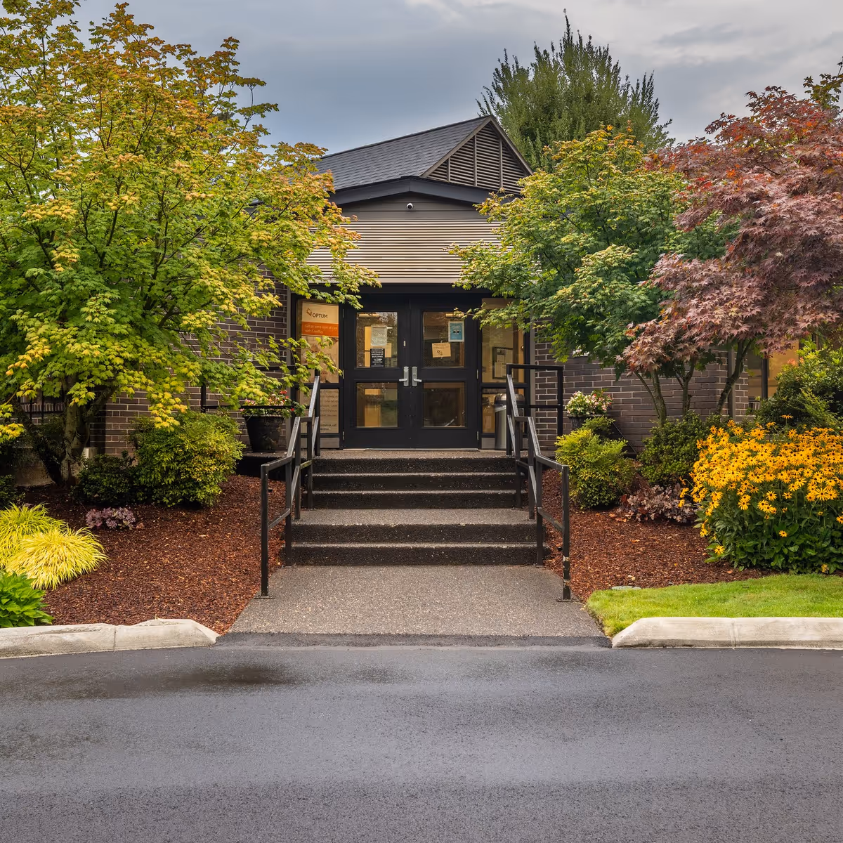Front entrance of Stanley Post Acute facility with steps, railing, and landscaped greenery.
