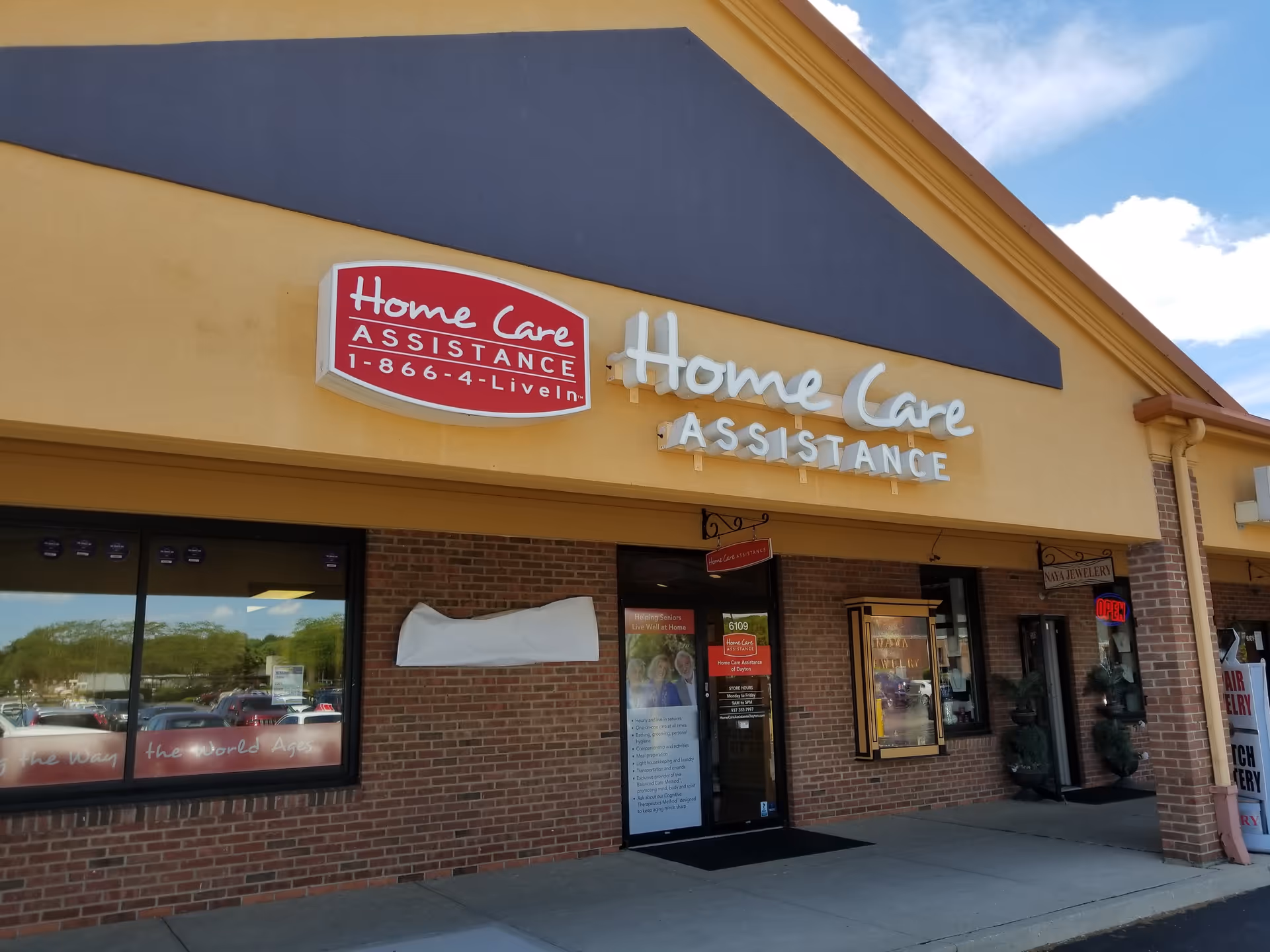 Exterior of a yellow storefront with Home Care Assistance signage and glass entrance