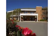 Front view of Milford Health Care Center with parking and blooming flowers.