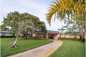 A single-story senior living facility with a curved walkway, green lawn, and trees.
