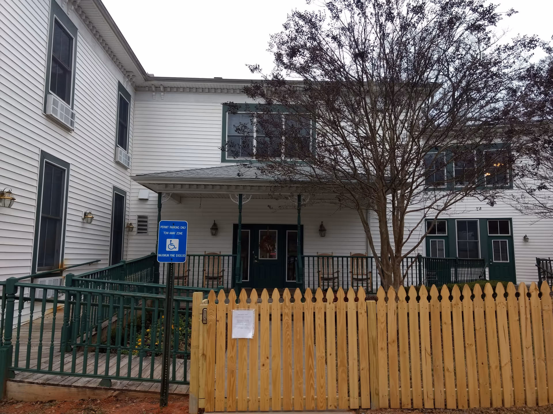 Exterior of Burnt Hickory Residences, a white building with green trim, fence, and tree.