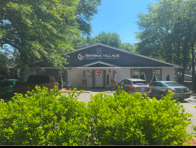 Front exterior of Smyrna Village memory care facility with parked cars