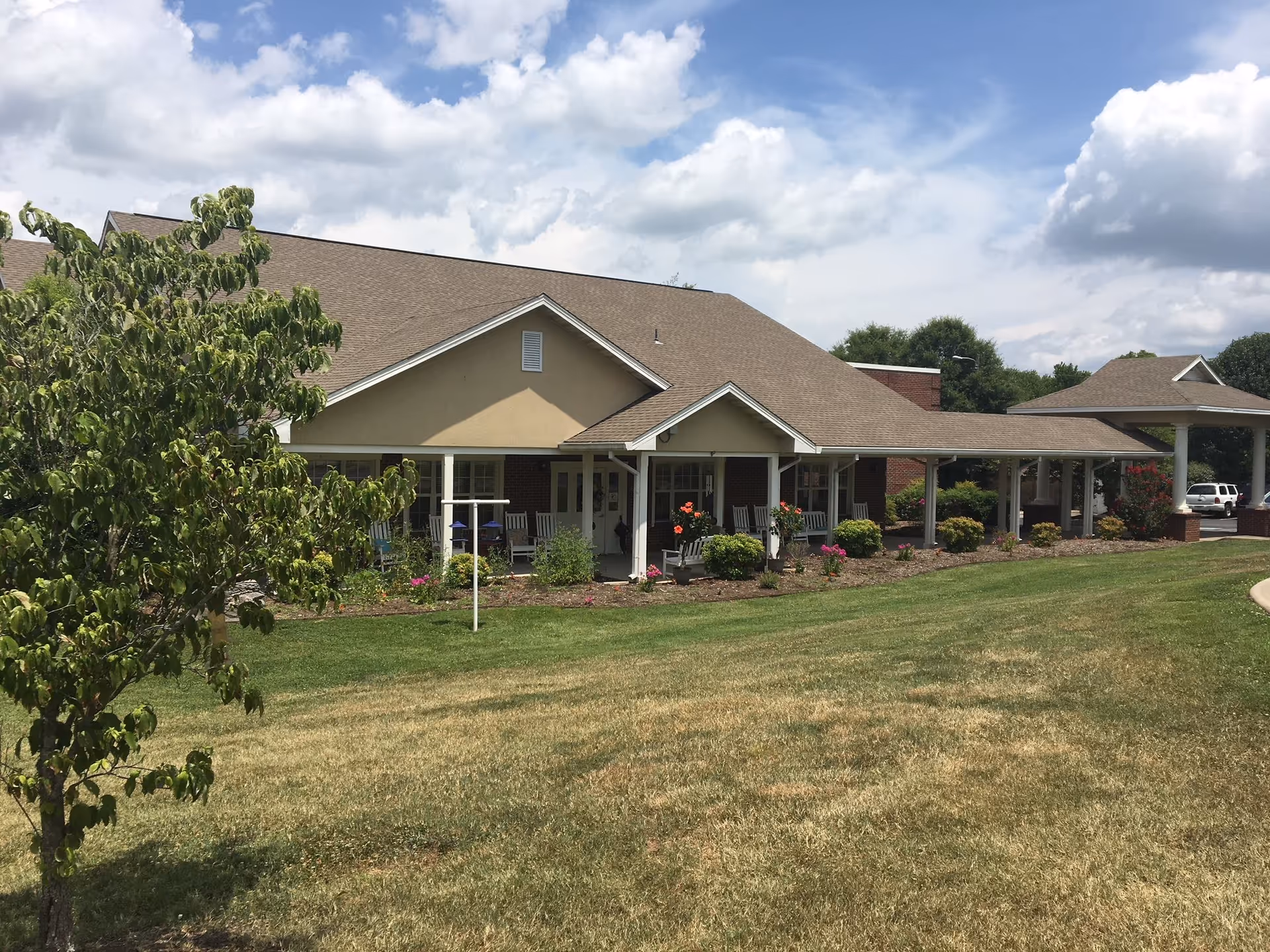 Single-story senior living facility with a wide covered porch and landscaped front lawn.