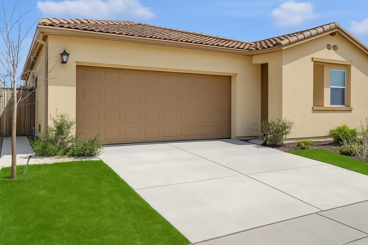 A beige single-story house with a two-car garage and green lawn.