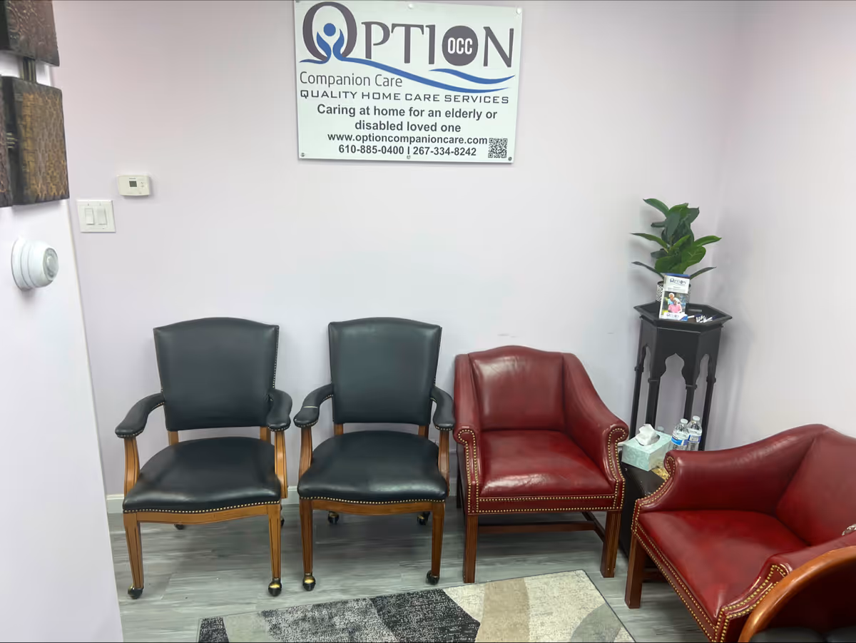 Waiting area with black and red leather chairs, a plant, and an Option Companion Care sign.