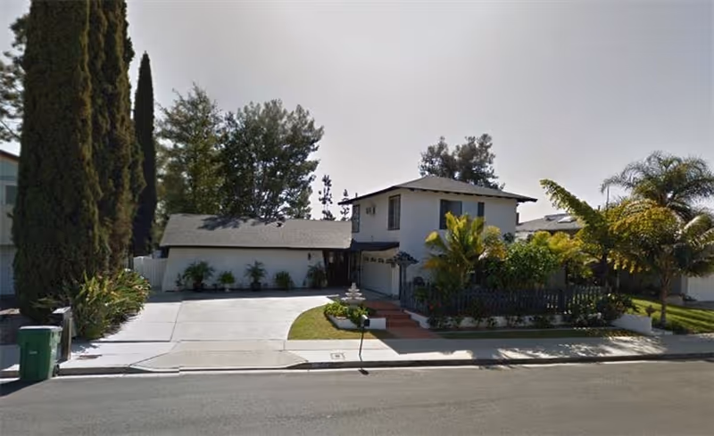 Front exterior of a two-story assisted living residence with driveway and landscaping.