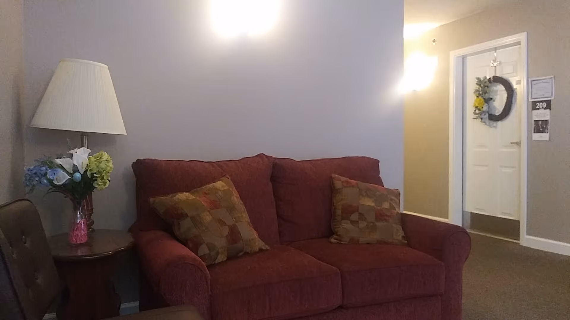 A red sofa with patterned pillows in a cozy living room of a senior housing unit.