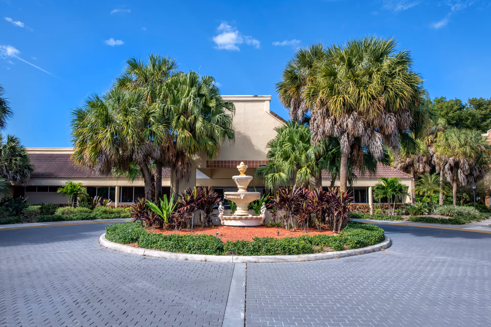 Front view of Brookdale West Palm Beach senior living facility with circular driveway and fountain.
