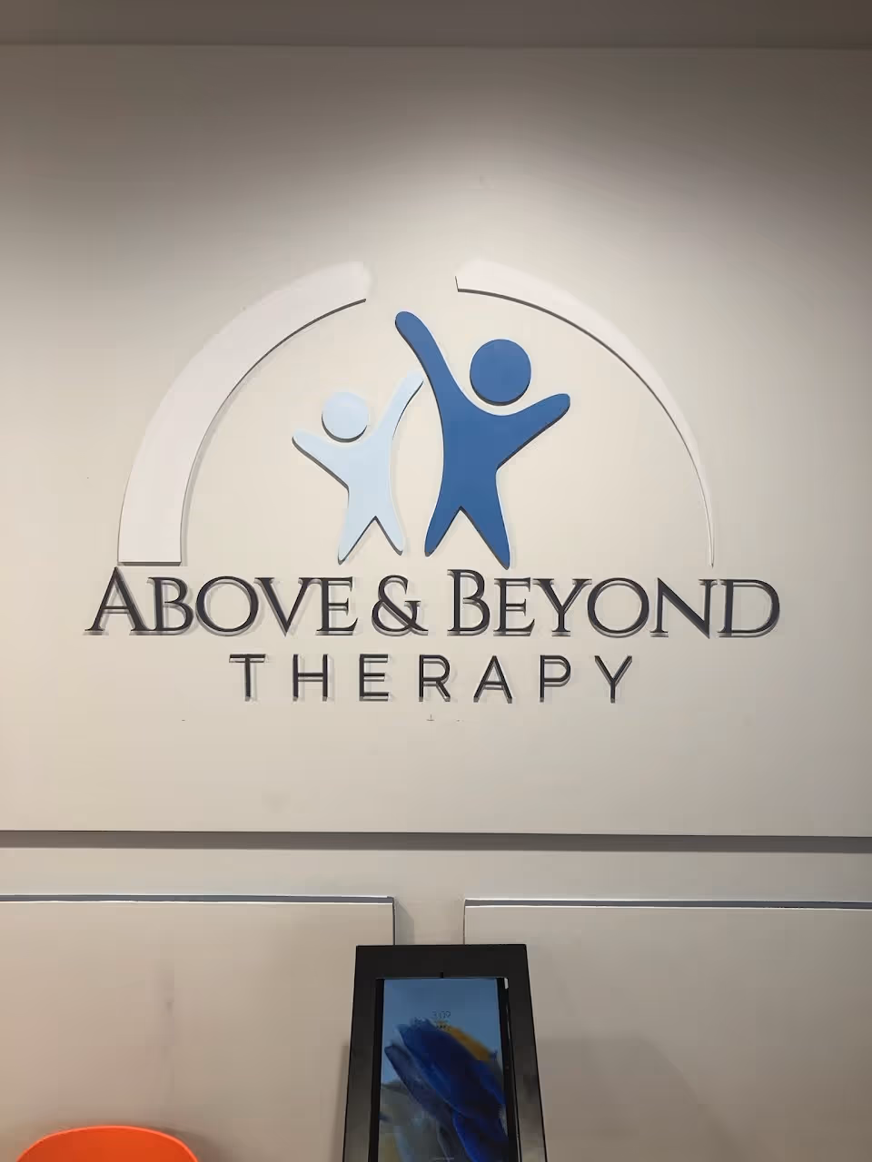 Indoor wall displaying the Above and Beyond Therapy logo with two abstract figures.